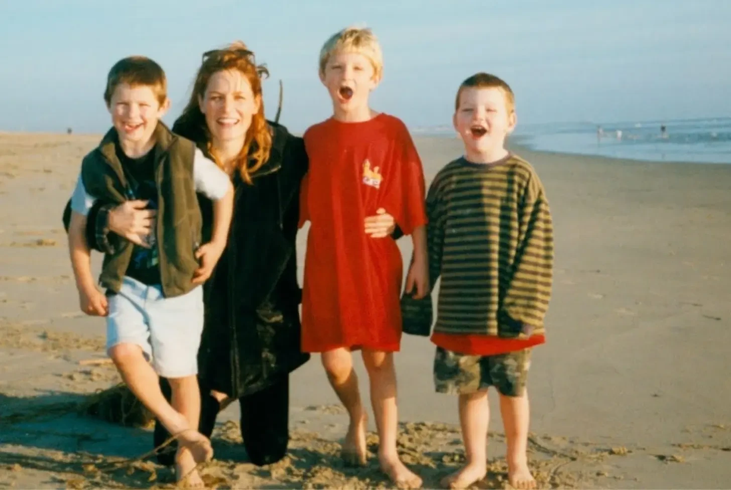 Anne with her three sons laughing on the beach