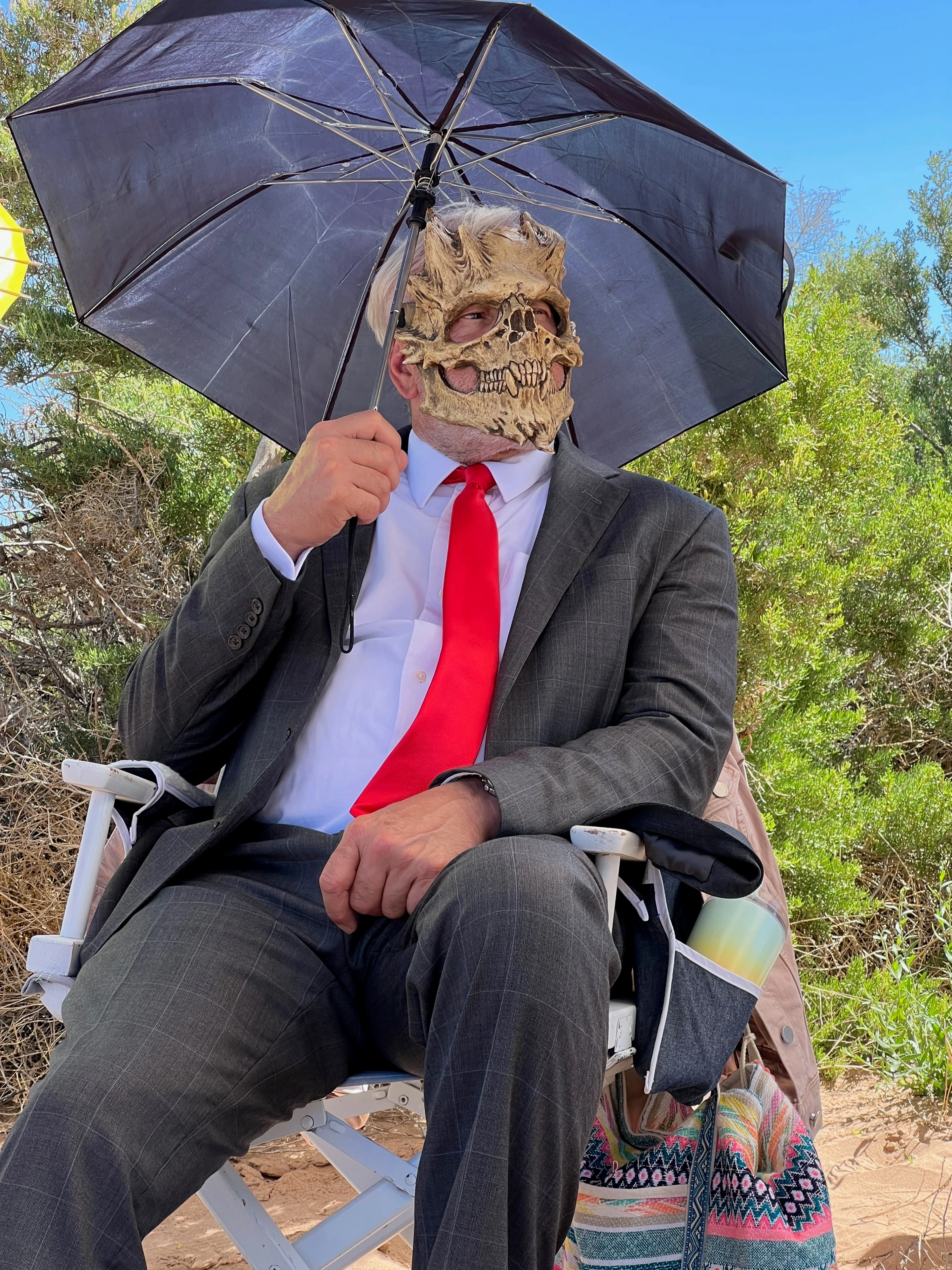 Tim in skull mask and suit with umbrella on set — F**k Your Face